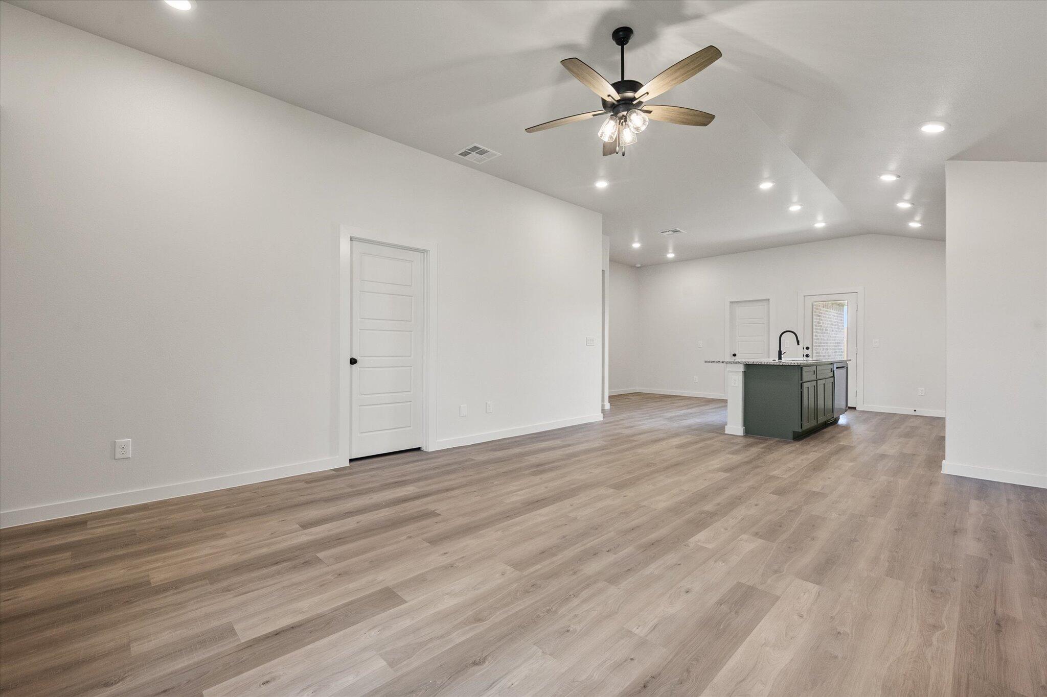 7215 8th Street Lubbock, TX 79416 - Photo 3 of 21 a view of an empty room with a chandelier fan and wooden floor