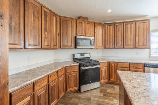 700 East Peter Springs Road Monticello, UT 84535 - Photo 9 of 57 Kitchen featuring extensive wood cabinetry, L-shaped countertops, stainless steel oven/range, and a built-in microwave
