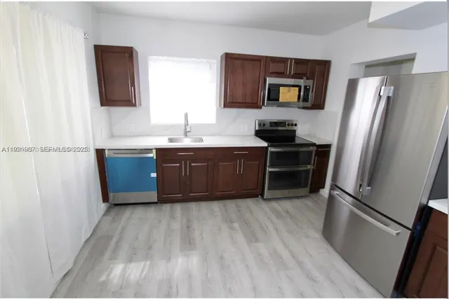 a kitchen with stainless steel appliances granite countertop a sink stove refrigerator and microwave