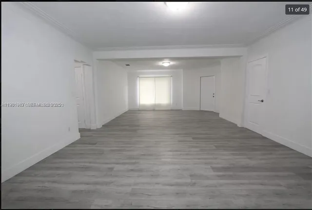 a view of empty room with window and wooden floor