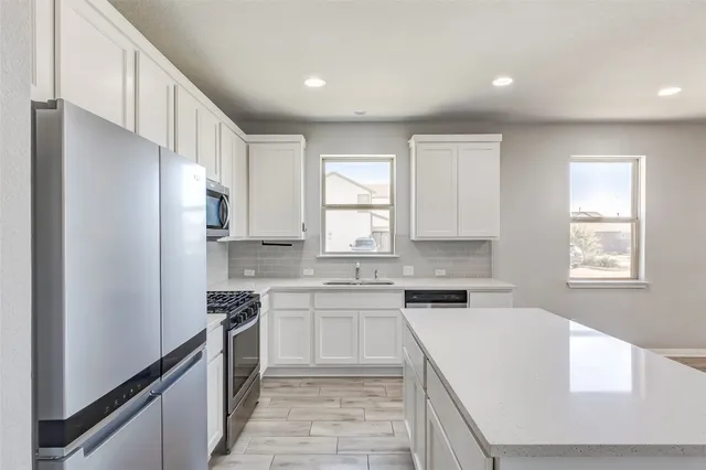 a kitchen with white cabinets and stainless steel appliances