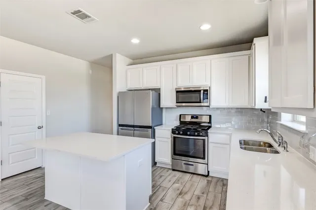 a kitchen with a sink a stove a refrigerator and cabinets