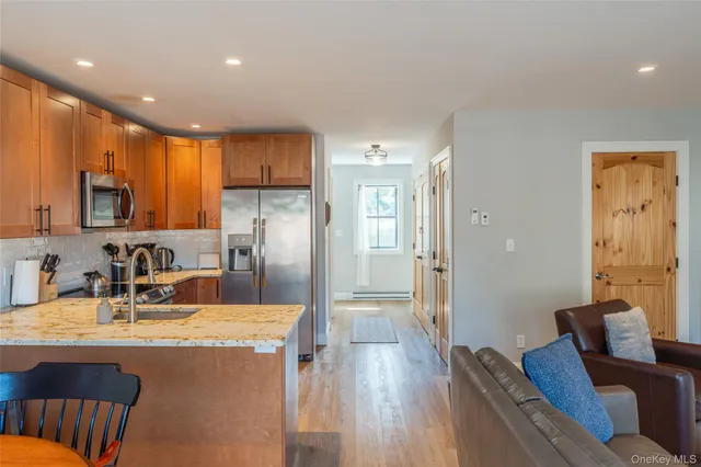 a kitchen with stainless steel appliances granite countertop a refrigerator a sink a stove a dining table and chairs