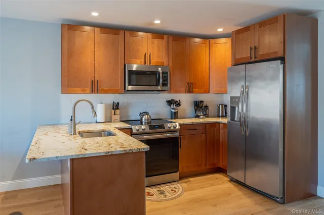 a kitchen with stainless steel appliances granite countertop a refrigerator a stove a sink and a microwave