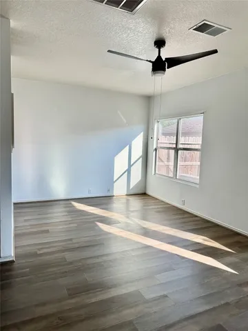 an empty room with wooden floor fan and windows