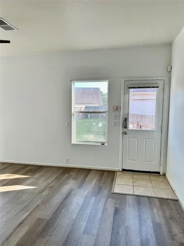 a view of an empty room with wooden floor and a window