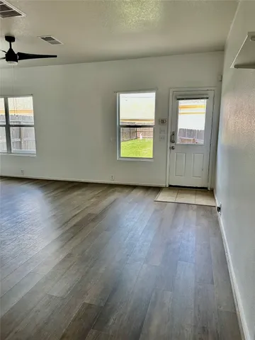an empty room with wooden floor and windows