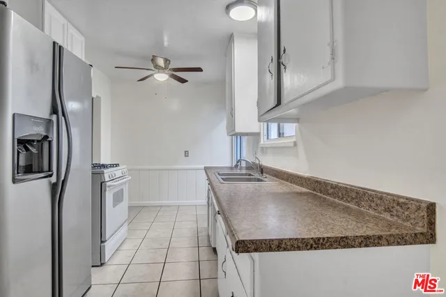 a kitchen with kitchen island a counter top space a sink a refrigerator and cabinets