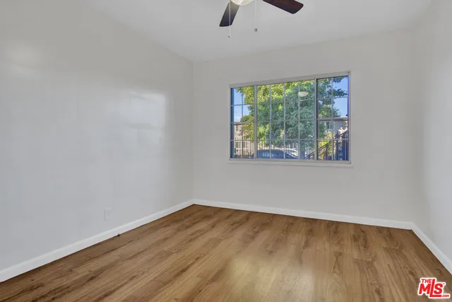 a view of an empty room with wooden floor and window