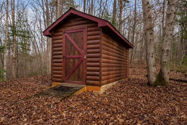 a view of wooden house with a small yard and large trees