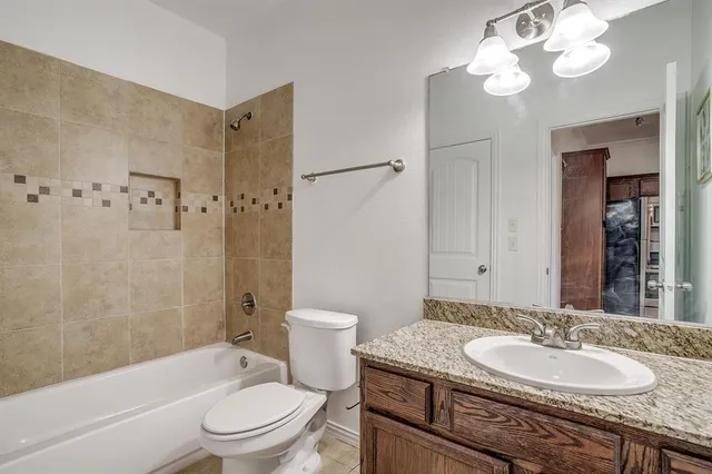 a bathroom with a granite countertop sink a toilet a mirror a bathtub and shower