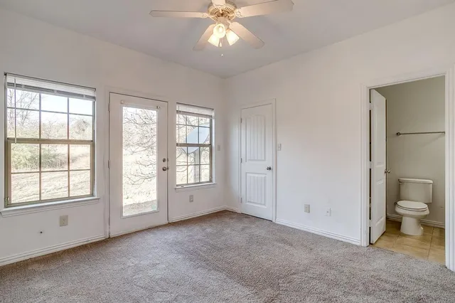 a view of an empty room with a window and bathroom