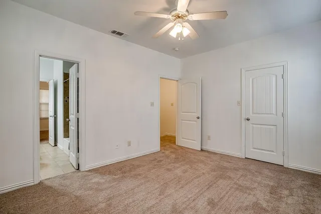 an empty room with closet and a chandelier fan