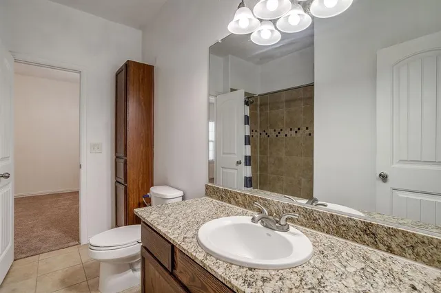 a bathroom with a granite countertop sink a toilet a mirror and shower curtain