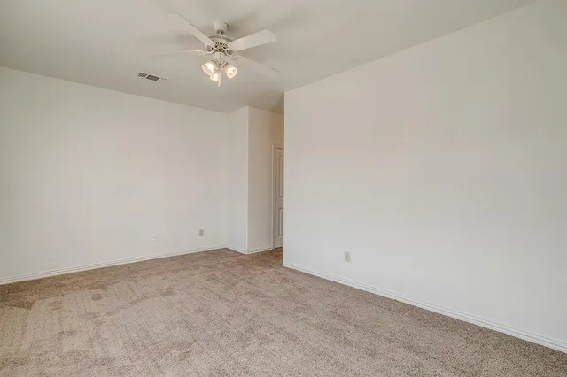 an empty room with a ceiling fan and a window