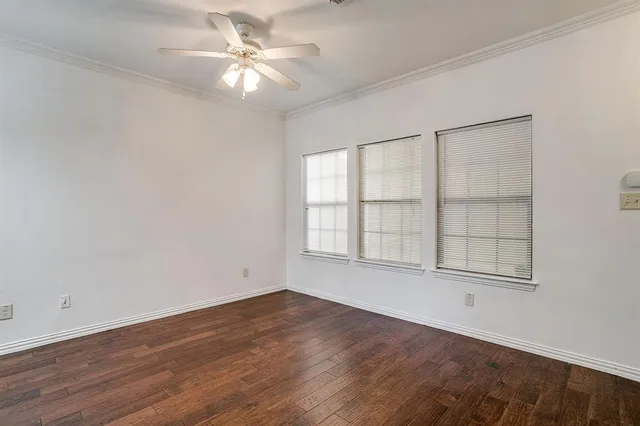 an empty room with wooden floor chandelier fan and windows