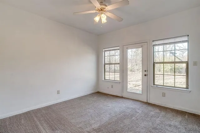 an empty room with chandelier fan and windows
