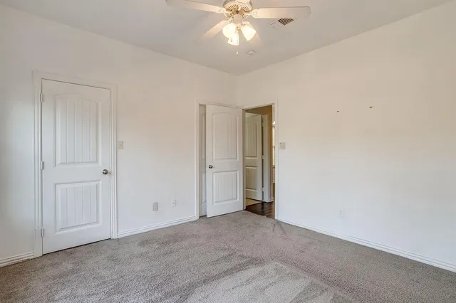 a view of an empty room and chandelier fan
