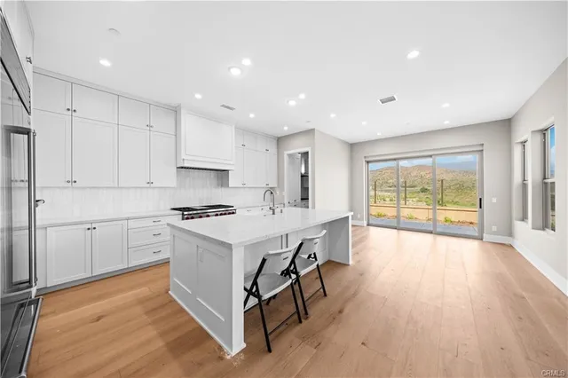 a large kitchen with stainless steel appliances granite countertop a stove and a large window