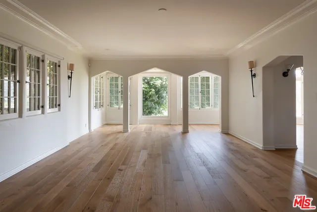 a view of an empty room with wooden floor and windows