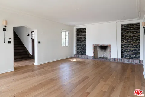 an empty room with wooden floor fireplace and windows