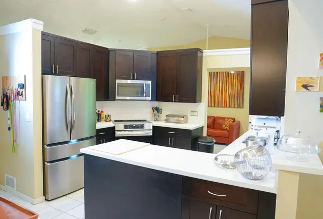 a kitchen with stainless steel appliances kitchen island granite countertop a refrigerator and a stove with wooden floor