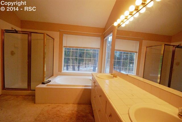 9575 Hardin Road Colorado Springs, CO 80908 - Photo 17 of 24 The master bathroom is joined to the master bedroom. This five-piece bath features tile counters, a large tub, spacious shower, water closet, and spacious walk-in closet.