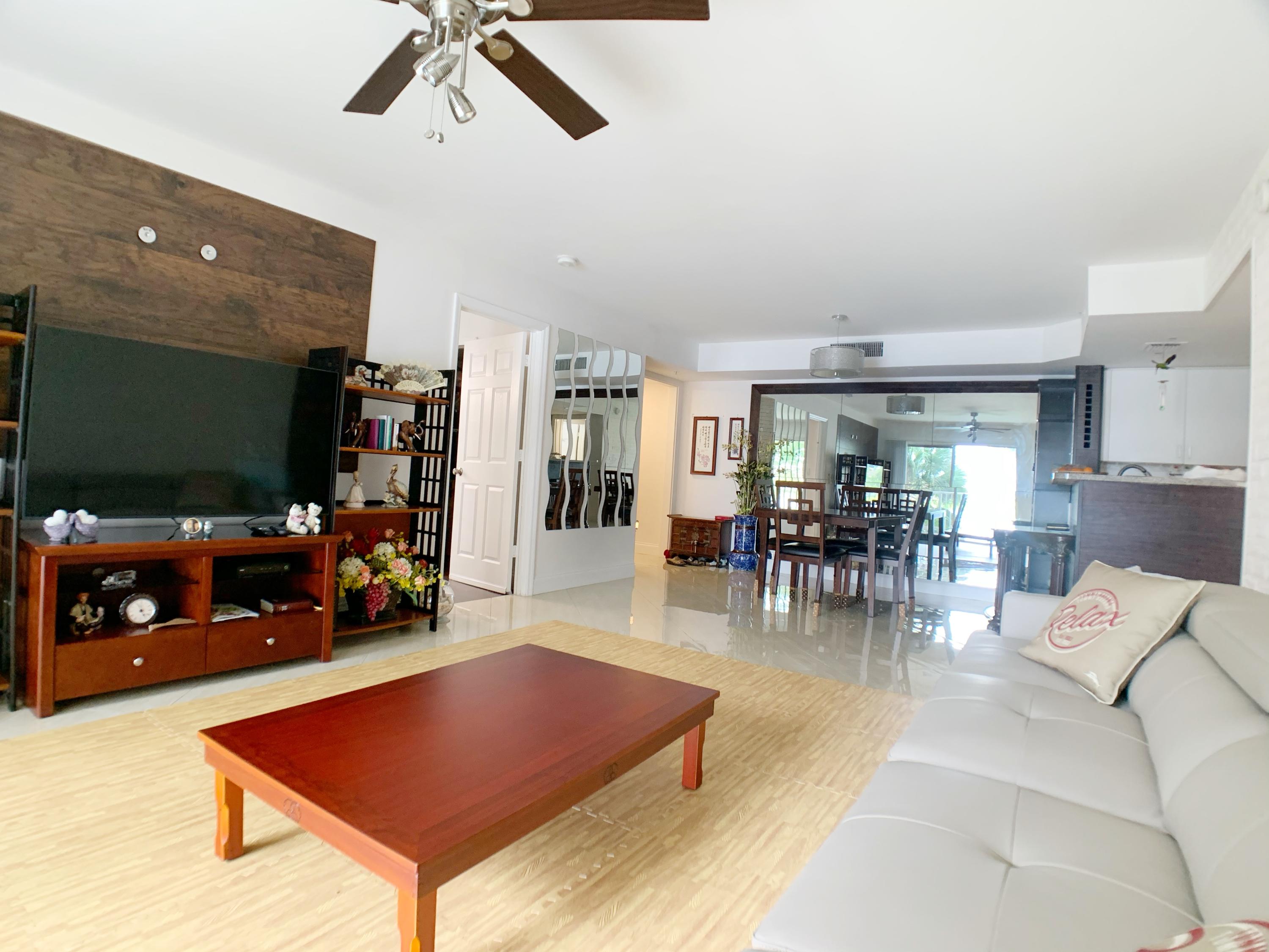 5015 Wiles Road, Unit 206 Coconut Creek, FL 33073 - Photo 12 of 32 a living room with furniture a dining table and a flat screen tv