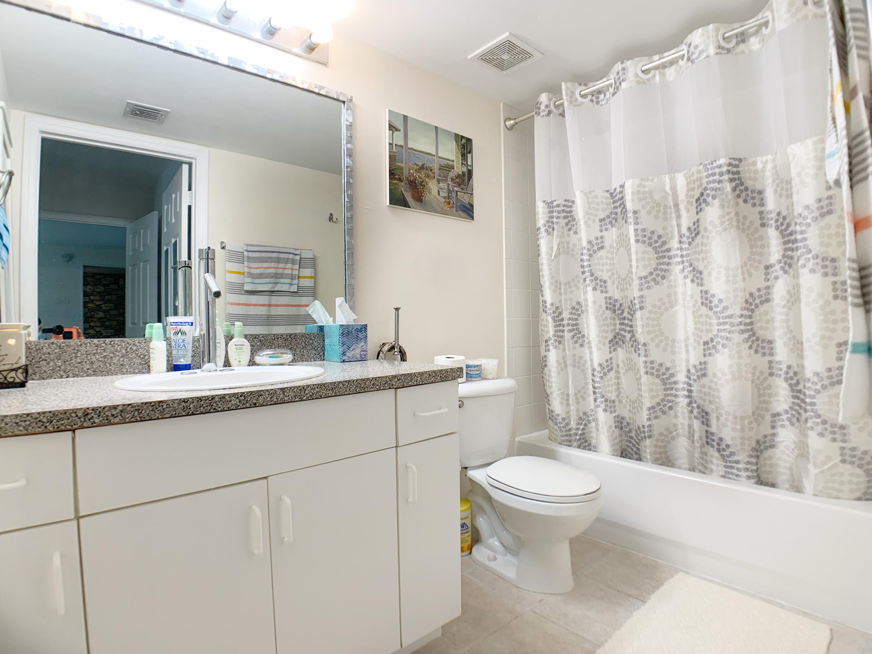 5015 Wiles Road, Unit 206 Coconut Creek, FL 33073 - Photo 27 of 32 a bathroom with a granite countertop sink a toilet and a mirror