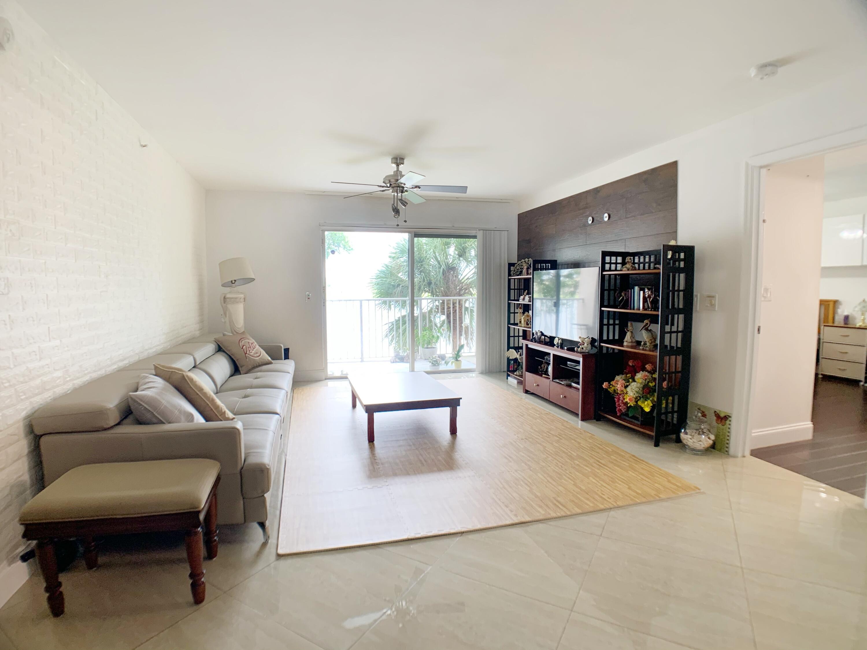 5015 Wiles Road, Unit 206 Coconut Creek, FL 33073 - Photo 5 of 32 a living room with furniture and a large mirror