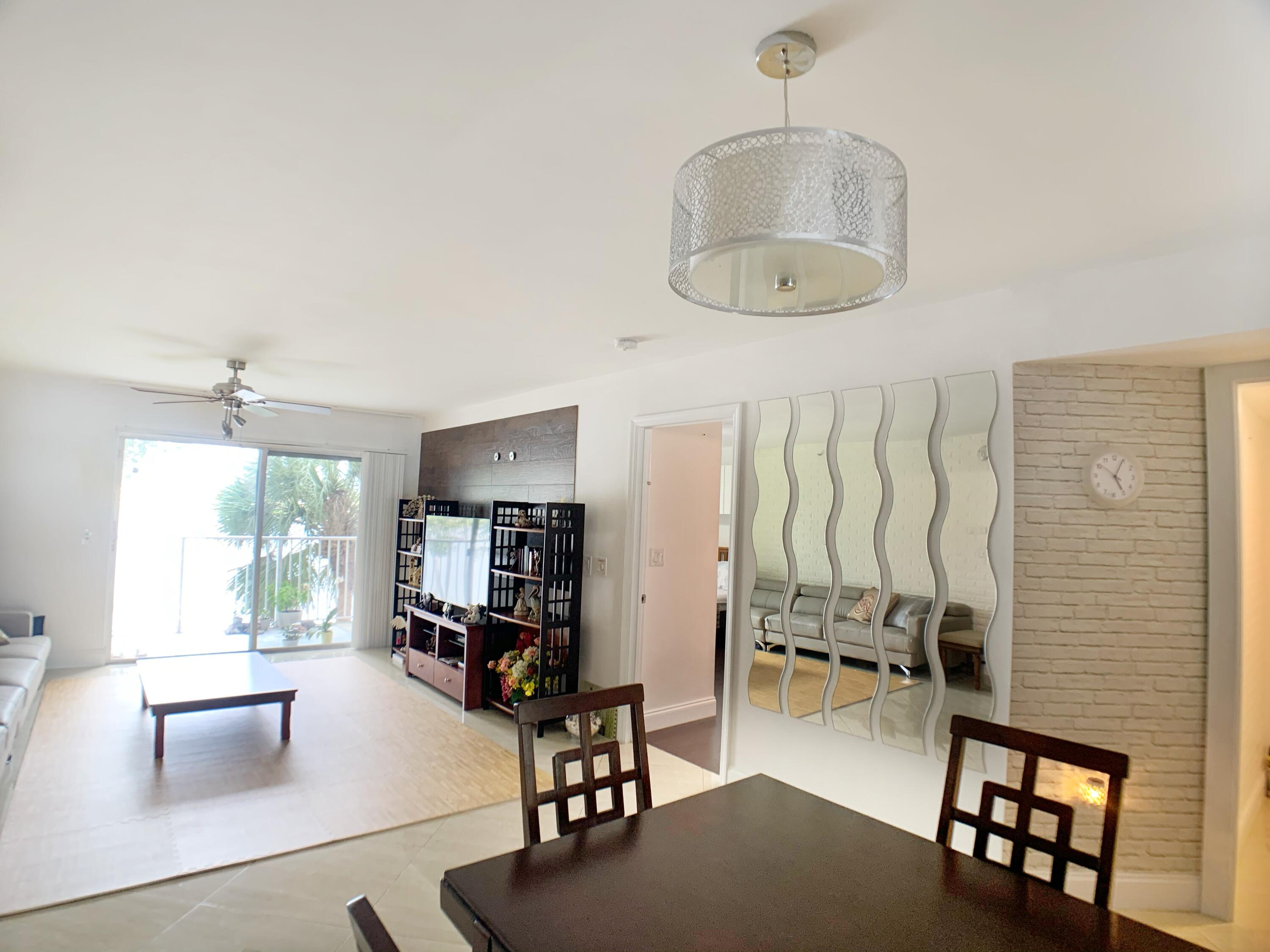 5015 Wiles Road, Unit 206 Coconut Creek, FL 33073 - Photo 7 of 32 a living room with furniture a window and a chandelier