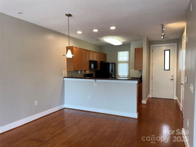 a view of a kitchen with a fridge and wooden floor
