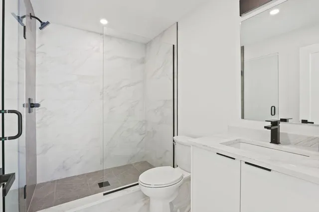 a bathroom with a granite countertop sink a toilet and shower