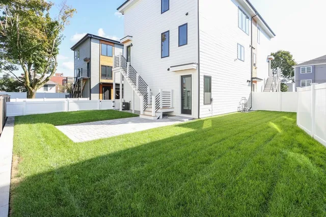 a view of a white house with a big yard and large trees