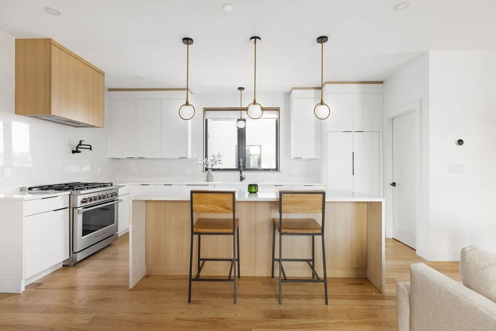 31 Hall Street, Unit 2 Waltham, MA 02453 - Photo 6 of 23 a kitchen with stainless steel appliances granite countertop a kitchen island a stove and a wooden floors
