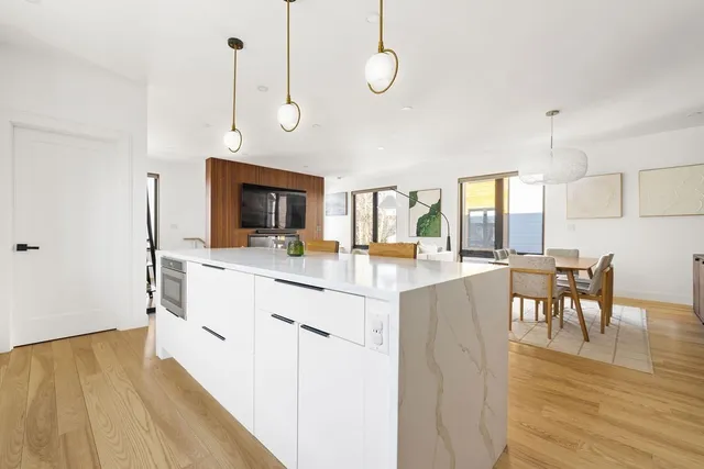 a kitchen with stainless steel appliances granite countertop a stove top oven a sink dishwasher a dining table and chairs with wooden floor