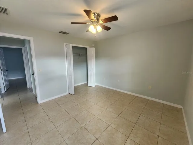 an empty room with closet and a chandelier fan