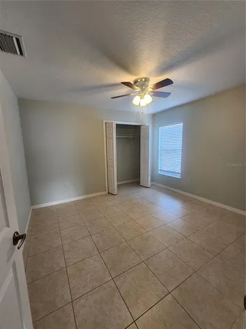 an empty room with windows and fan
