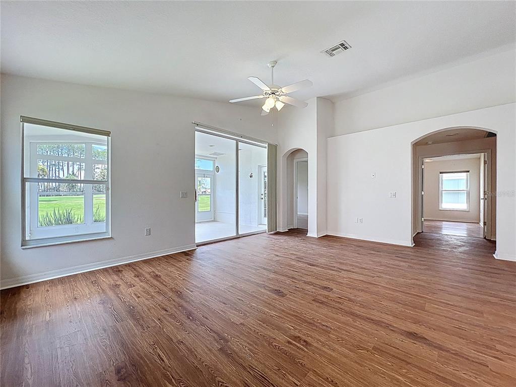 11644 Spindrift Loop Hudson, FL 34667 - Photo 23 of 99 an empty room with wooden floor chandelier fan and windows