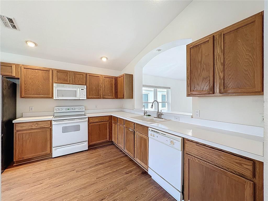 11644 Spindrift Loop Hudson, FL 34667 - Photo 9 of 99 a kitchen with a sink cabinets wooden floor and stainless steel appliances