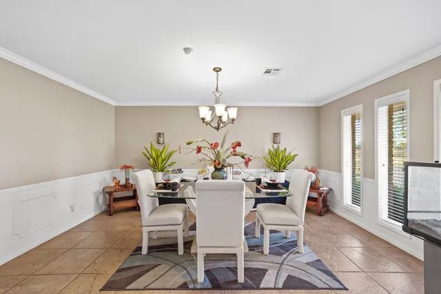 a dining room with furniture a potted plant and a large mirror