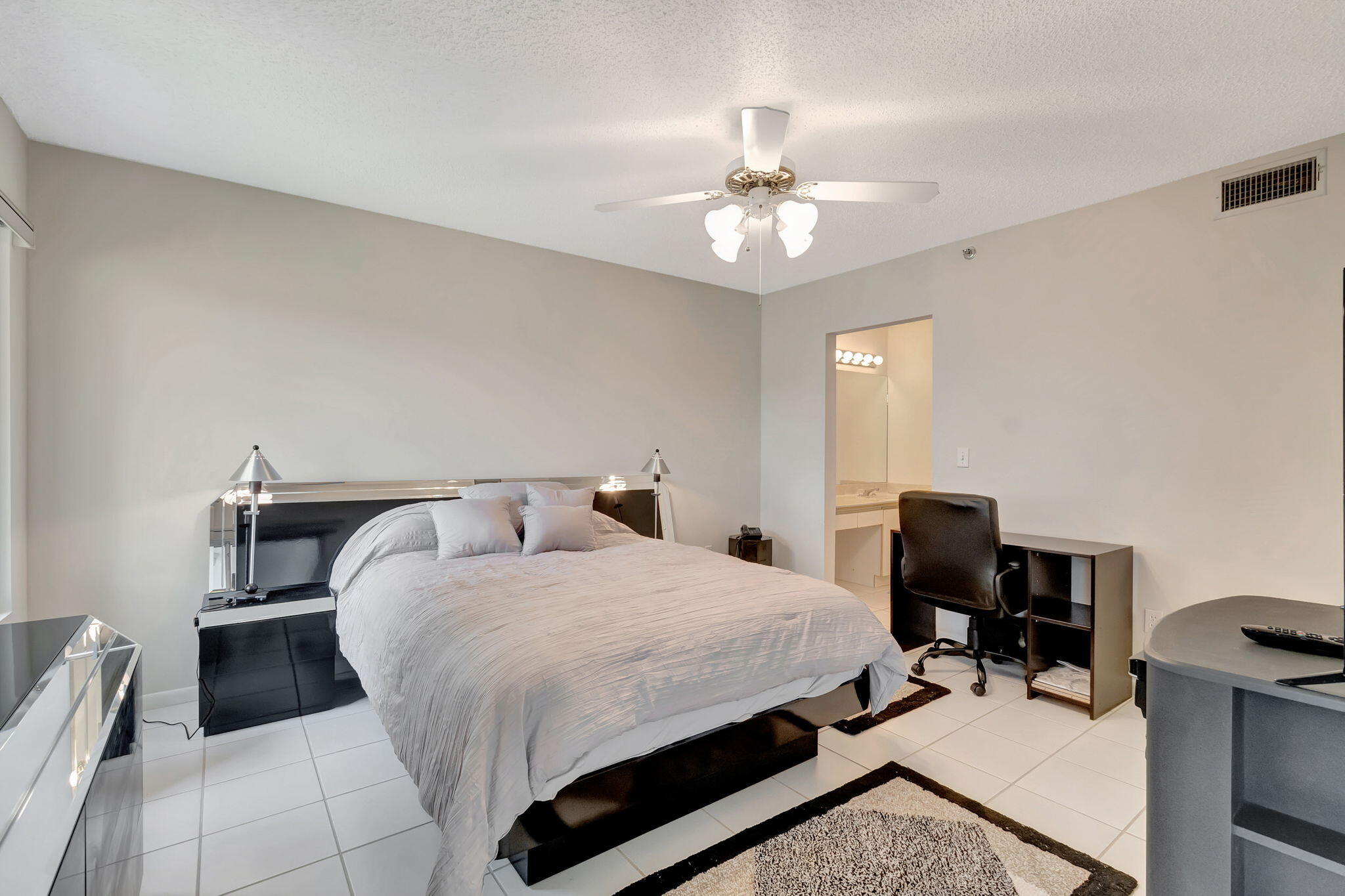 280 Northwest 67th Street, Unit B207 Boca Raton, FL 33487 - Photo 16 of 22 a bedroom with a bed and a table chair