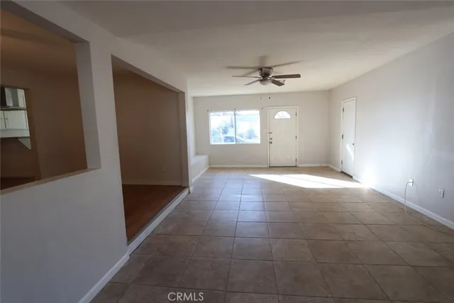 a view of an empty room with window and chandelier fan