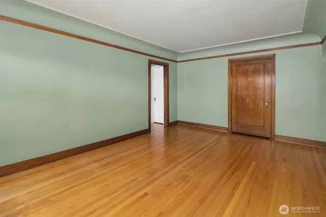 a view of an empty room with window and wooden floor