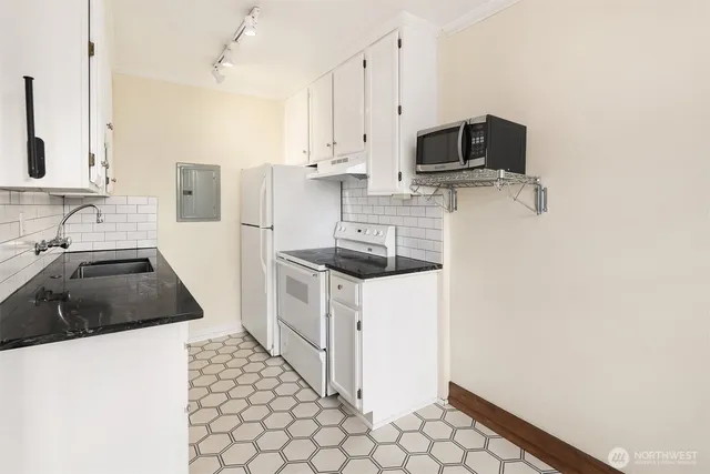 a kitchen with granite countertop a sink a stove and cabinets
