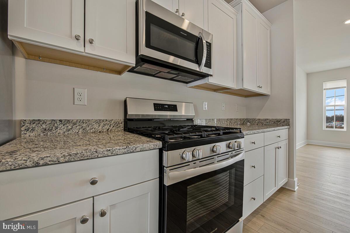 7268 Contee Road Laurel, MD 20707 - Photo 18 of 42 a kitchen with stainless steel appliances granite countertop white cabinets and a stove top oven
