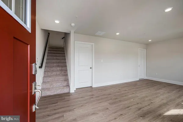 an empty room with wooden floor and staircase