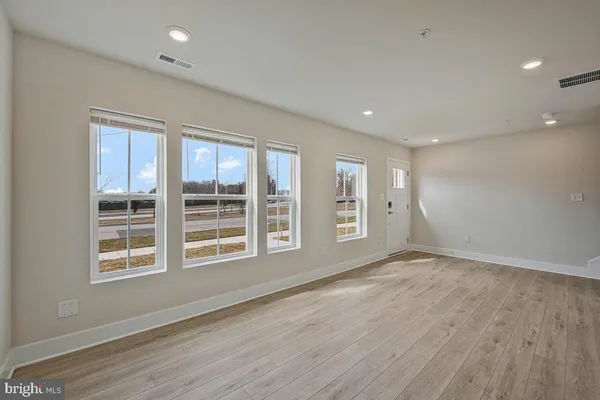 a view of an empty room with a window and wooden floor