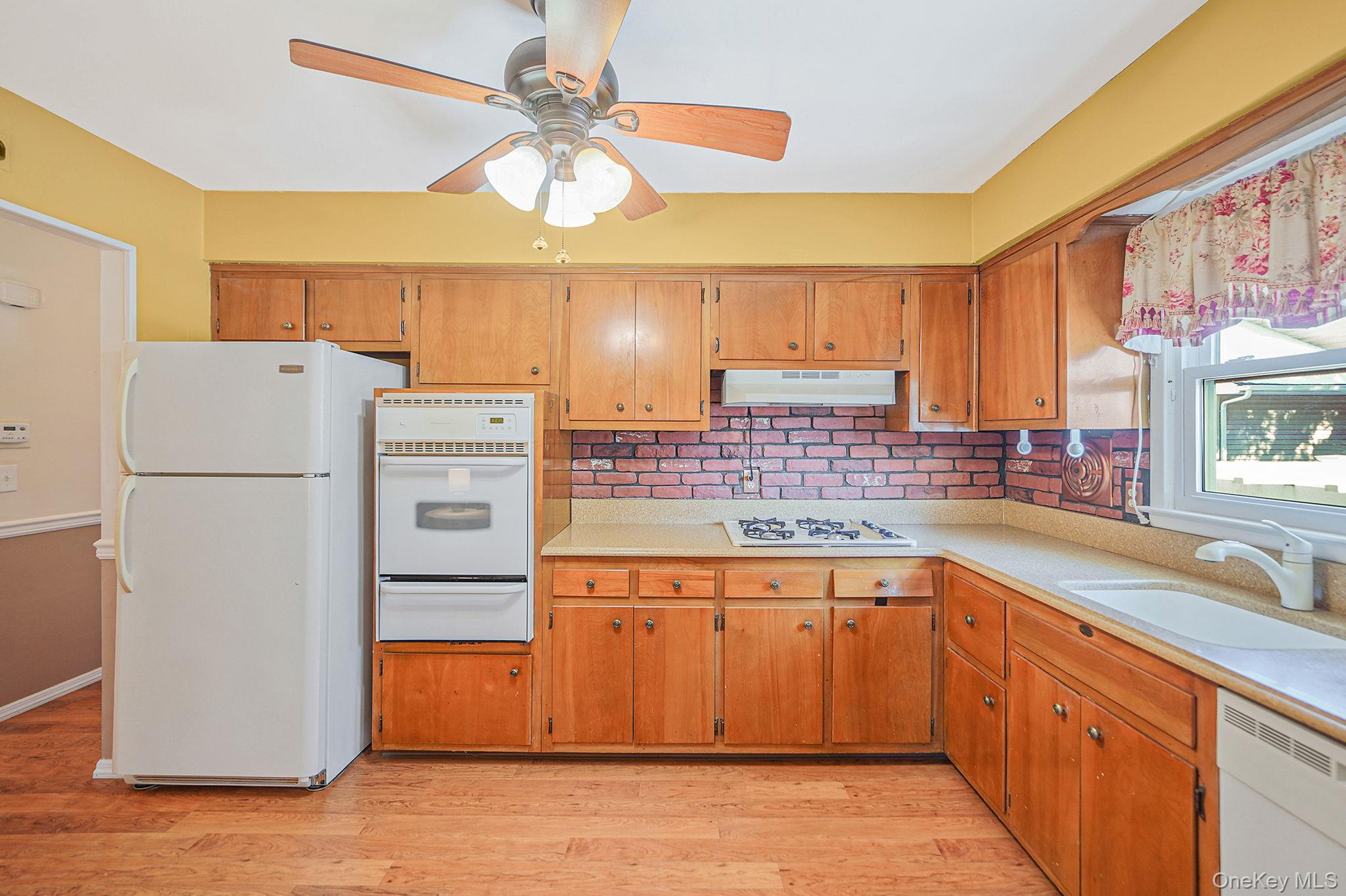 2009 Newbridge Road Bellmore, NY 11710 - Photo 13 of 24 a kitchen with a refrigerator a sink and dishwasher with wooden floor
