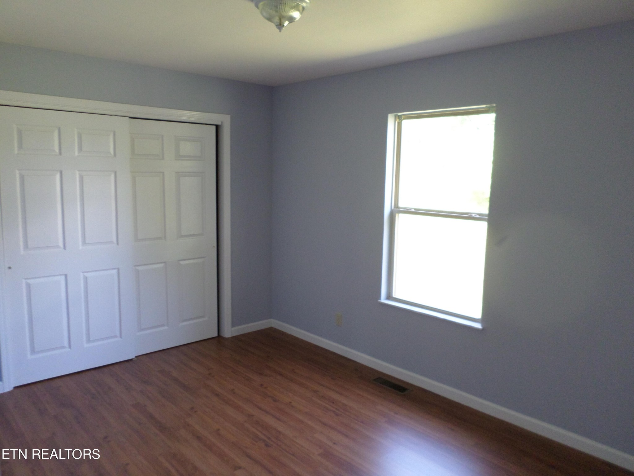 236 Woods Road Oliver Springs, TN 37840 - Photo 9 of 23 an empty room with wooden floor and windows